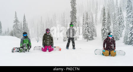 Les snowboarders s'agenouiller et reposant à Sun Peaks Resort ; Kamloops, British Columbia, Canada Banque D'Images