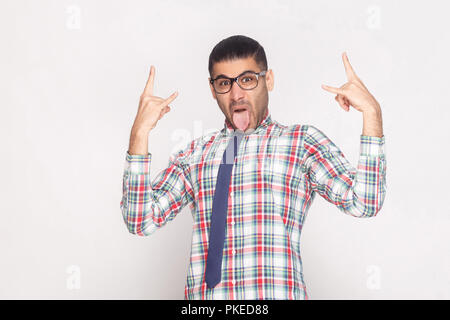 Rock and Roll. crazy funny businessman barbus en chemise à carreaux colorés, cravate bleue et lunettes noires, permanent avec la langue. Banque D'Images