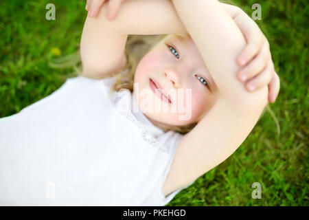 Cute little girl s'amusant sur un gazon sur l'arrière-cour par beau soir d'été. Activités d'été pour les enfants. Vue de dessus. Banque D'Images