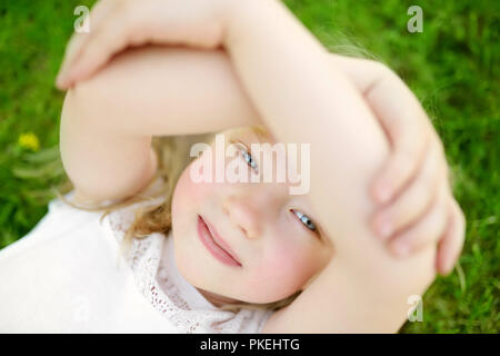 Cute little girl s'amusant sur un gazon sur l'arrière-cour par beau soir d'été. Activités d'été pour les enfants. Vue de dessus. Banque D'Images