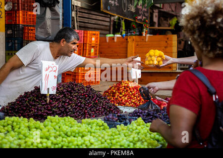 Vendeur de fruits dans un T-shirt blanc sur le marché Carmel à Tel Aviv, Israël Banque D'Images