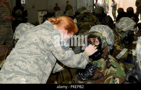 ALPENA, Michigan-- instructeur avec le 127e Escadron de génie civil aide Tech Sgt. Daniels Chanel, 127e Escadron de soutien de la Force, en ajustant son masque à gaz pendant la bataille de la formation au laboratoire Alpena préparation au combat Center le 29 juillet 2018. Au cours de la formation, des aviateurs de la 127e Escadre, comme Daniels, pratiqué l'enfilage et le retrait des différents niveaux de l'équipement de protection chimique au cours d'un exercice d'évaluation de l'état de préparation opérationnelle. Banque D'Images