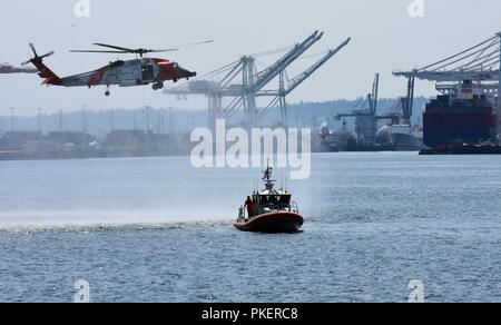 Un secteur de la Garde côtière de la rivière Columbia hélicoptère Jayhawk MH-60 équipage effectue une recherche et sauvetage de la Garde côtière de démonstration aux côtés d'un équipage de bateau, Seattle Station à bord d'un 45 pieds en réponse Boat-Medium Elliott Bay, Washington, le 31 juillet 2018. En plus de la démonstration, de nombreux navires de la Marine américaine, la Garde côtière et la Marine canadienne ont participé à l'événement annuel. La Garde côtière américaine Banque D'Images