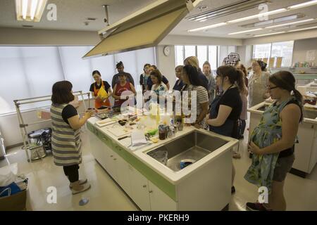 Marine Corps Air Station (MCAS) les résidents se retrouvent autour d'Iwakuni Sachiko Tamura, un chef avec la Ville Iwakuni Association de Promotion de l'alimentation, pendant un cours de cuisine à Otake City, Japon, Juillet 28, 2018. Le cours de cuisine, organisé par le programme d'adaptation culturelle, a été organisée afin de montrer MCAS Iwakuni résidents comment faire des plats traditionnels japonais et d'acheter des composants à un magasin local. Banque D'Images