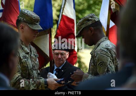 Les soldats de la Garde nationale d'armée à partir de la 42e Division d'infanterie, pliez un drapeau américain lors d'une cérémonie à dédier une plaque en l'honneur du général Douglas MacArthur sur la PREMIÈRE GUERRE MONDIALE Bataille Meuse-Argonne en France, 25 juillet. Les soldats des unités qui composent la 42e Division au cours de la PREMIÈRE GUERRE MONDIALE a participé à la deuxième phase d'une année de commémoration du centenaire de la PREMIÈRE GUERRE MONDIALE dans le nord de France de juillet 24 - 29. Banque D'Images