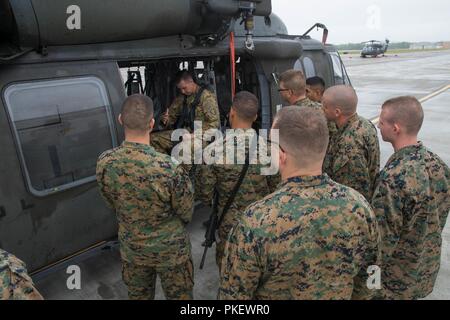 Chefs et sélectionner le personnel de soutien, à partir de la 4e Division de marines, concours annuel de peloton de recevoir des leçons sur la façon de bien et rouler dans une armée américaine Sikorsky UH-60 Black Hawk à Joint Base Elmendorf-Richardson, Anchorage, Alaska, le 1 août, 2018. Chefs de peloton de l'Assemblée annuelle de la concurrence ont levé des sites tout au long de la formation afin d'effectuer la reconnaissance de route avant le début de la compétition de quatre jours. Banque D'Images