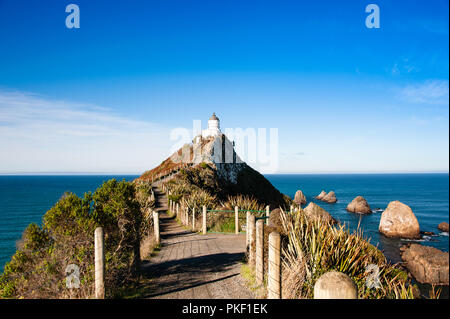 Nugget Point Lighthouse, Côte Catlins, Nouvelle-Zélande. Scène à couper le souffle, premier plan, océan et le ciel bleu profond Banque D'Images