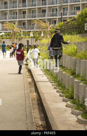 L'Okinawa, Japon, CHATAN - Membres de l'Université de l'équipe de football des pastenagues Ryukyu recueillir corbeille lors d'une journée de l'amitié nettoyage de plage le 4 août sur la plage de Sunset sea wall, Chatan dans Okinawa, Japon. Quatre équipes avec les forces américaines au Japon - American Football League nettoyé corbeille autour de la digue et déguster un repas après. Le nettoyage permettait aux joueurs de toutes les équipes de passer du temps ensemble sur le terrain de football et de travailler ensemble pour prendre soin de leur communauté. Banque D'Images