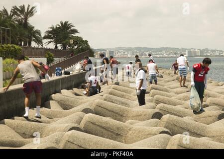 L'Okinawa, Japon, CHATAN - Les membres des forces américaines au Japon - American Football League nettoyer la corbeille au cours d'une journée de l'amitié nettoyage de plage le 4 août au Sunset Beach seawall en Chantan, Okinawa, Japon. Les rois Dragons Kinser, Kadena, Camp Hansen Outlaws, et l'Université de Ryukyu Stingrays ont passé la journée à nettoyer les ordures autour de la digue et bénéficient d'un repas après. Le nettoyage permettait aux joueurs de toutes les équipes de passer du temps ensemble sur le terrain de football et de travailler ensemble pour prendre soin de leur communauté. Banque D'Images