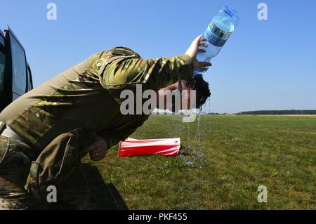 U.S. Air Force Tech. Le Sgt. Joshua Todd, 435ème Groupe d'intervention d'urgence, spécialiste météo verse de l'eau sur sa tête en attendant une enquête auprès de la zone d'atterrissage à la base aérienne de Powidz, Pologne, le 1 août 2018. Réponse d'aviateurs, sortir à une variété d'environnements hostiles et austère d'établir les sites cruciaux pour la réalisation de la mission. Banque D'Images