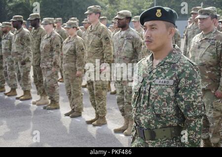 Le Cpt. Mohammed Fikri bin Mohammad Ramli 15e Régiment Malais Royal actuel, à l'attention devant une formation de soldats de l'Armée américaine au cours de la cérémonie de clôture de l'exercice Keris Grève, 3 août 2018. Exercice Keris grève a été un exercice bilatéral entre la Malaisie et les États-Unis, en mettant l'accent sur l'aide humanitaire et les opérations de secours. Banque D'Images