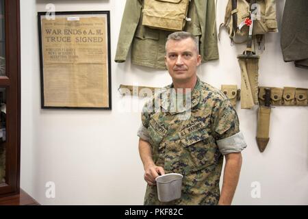 Le Lieutenant-Colonel Timothy Silkowski, directeur général, Marine Corps Base Barstow, est la tenue d'une cantine militaire vintage cup devant un mur couvert de souvenirs militaires dans son bureau au quartier général de commandement. Le nouveau XO d MCLBB est un historien passionné et restaurateur de véhicules militaires d'époque. Banque D'Images