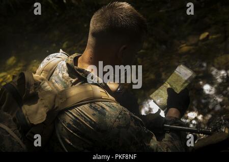 Lance le Cpl. Damion Merrow, un carabinier avec Echo, l'entreprise Équipe de débarquement du bataillon, 2e Bataillon, 5ème Marines, fait référence à une carte pendant un cours de navigation terrestre au Jungle Warefare Training Centre, Okinawa, Japon, Juillet 31, 2018. Merrow, originaire de Thamel, Oregon, a fait appel à des sous-station recrutement percé. Les marines formés à se préparer à une ETFC patrouille à venir de la région indo-pacifique comme l'élément de combat terrestre pour la 31e Marine Expeditionary Unit. La 31e MEU, le Marine Corps' seulement continuellement de l'avant-déployés MEU, fournit une force flexible prêt à effectuer une vaste gamme o Banque D'Images