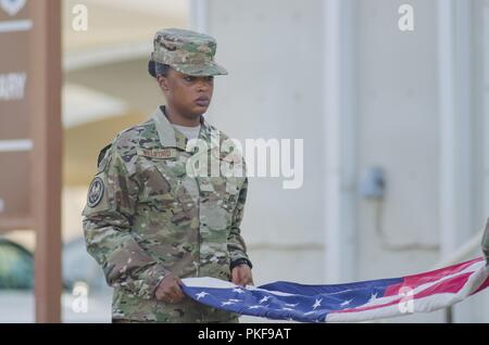 Destin, Senior Airman Alyson Cambridge 380e Escadre expéditionnaire de la garde d'honneur tient le drapeau américain qu'il est plié lors d'une retraite cérémonie à la base aérienne d'Al Dhafra aux guerriers tombés au champ d'honneur, le 3 août 2018. Le 380e honneurs militaires décédés au cours de l'AR une fois par mois avec une retraite cérémonie. Banque D'Images