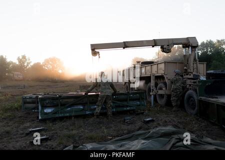 La CPS. Cody Jensen, camionneur, 147e de l'avant Support Compagnie, 1er Bataillon, 147e Régiment d'artillerie, Roslyn, S.D., guides une balise d'un tube de missiles Système de lance-roquettes multiple sur un chariot vide sous la forme d'un lit. Steven Smith, camionneur, 147e FSC, exploite le système de treuil sur 10 Août, 2018. Le Dakota du Sud les soldats de la Garde nationale d'Armée participent à Northern Strike, une multinationale interarmées exercice de tir réel interarmes au Camp Grayling, Mich. Banque D'Images