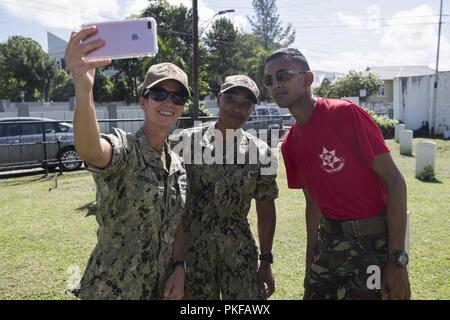 PORT OF SPAIN, Trinité-et-Tobago (16 août 2000 10, 2018) La commande Master Chief Kimberly Ferguson, prend un d'un marin selfies stationnée sur le Island-Class Whidbey Landing Ship Dock USS Gunston Hall (LSD 44) et un membre du service de la Trinité-et-Tobago Regiment au cours d'une relation communautaire événement à un cimetière militaire à Port of Spain, Trinité-et-Tobago. Le navire est en déploiement des Mers du Sud, qui est un déploiement de collaboration annuel dans le U.S. Southern Command zone de responsabilité où un groupe se déployer pour effectuer une variété d'exercices et d'échanges multinationaux Banque D'Images