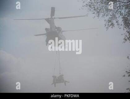 Un hélicoptère CH-47 Chinook du 2e Bataillon de l'aviation d'appui général, 135e Régiment d'aviation, Colorado, la Garde nationale commence d'un ascenseur, d'un obusier M777 105mm près du camp de l'Arctique, Michigan au cours de Northern Strike 18 Août 10, 2018. Banque D'Images