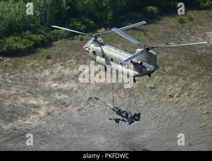 Un hélicoptère CH-47 Chinook du 2e Bataillon de l'aviation d'appui général, 135e Régiment d'aviation, la Garde nationale du Colorado, l'air soulève un obusier M777 105mm du Camp Grayling, Michigan à un domaine dans les environs de la préparation au combat au Centre à Alpena, Michigan, le 10 août 2018. Banque D'Images