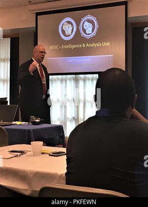 Michael Hemberger, analyste à l'échelle de l'État du Wisconsin Intelligence Center, les adresses des participants à la réunion de l'équipe de gestion des menaces 2018 9 août, 2018, à McCoy's Community Center de Fort McCoy, Wisconsin (Etats-Unis) C'était la huitième réunion annuelle de l'équipe qui regroupe des personnes de Fort McCoy ainsi que les forces de l'ordre, la sécurité, et des organismes de services d'urgence de l'ensemble du Wisconsin. Le but de la réunion et l'équipe est de faciliter la mise en réseau et de développer les connaissances des participants concernant diverses menaces possibles dans le pays aujourd'hui. Banque D'Images