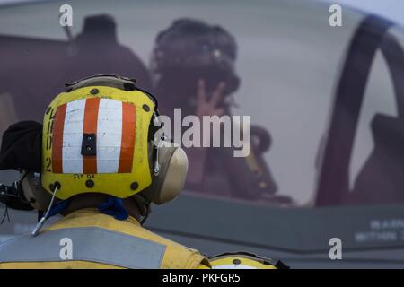 Océan Pacifique - U.S. Marine Le capitaine Nicholas Koza, un F-35B II d'éclairage avec pilote de chasse Marine Attack Squadron 211, 13e Marine Expeditionary Unit (MEU), donne un signal de la main pour le décollage de la Marine américaine à Maître de 1re classe Rey blanc, un boatsmate avec le gestionnaire de l'aviation Amphibie Essex Group (ARG), à bord de la classe Wasp-navire d'assaut amphibie USS Essex (DG 2), lors d'un déploiement prévu d'Essex ARG et la 13e MEU, le 31 juillet 2018. L'Essex ARG/MEU est une équipe solide, souple, réactive et cohérente capable de la guerre de manœuvre dans tous les domaines ; il est é Banque D'Images