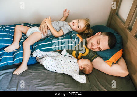 Jeune homme au lit avec les enfants Banque D'Images