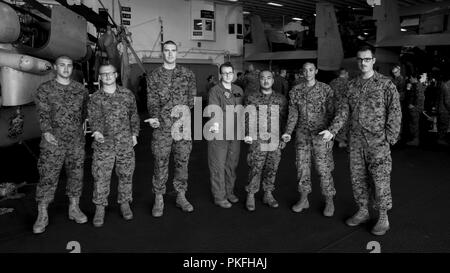 Océan Pacifique - Les Marines américains et les marins de la marine à partir de la 13e Marine Expeditionary Unit (MEU), posent pour une photo avec des pièces de défi qui leur avait été présenté par le colonel des marines américain Chandler Nelms (à gauche), Commandant, 13e MEU, pour leur travail remarquable dans leurs sections respectives, lors d'un déploiement prévu de la Essex Groupe amphibie (ARG) et la 13e MEU, le 29 juillet 2018. L'Essex ARG/ 13e MEU est capable d'une mortelle et Navy-Marine Corps équipe déployée à la 7e flotte zone d'opérations pour soutenir la stabilité régionale, de rassurer les partenaires et alliés et maintenir une présence pos Banque D'Images