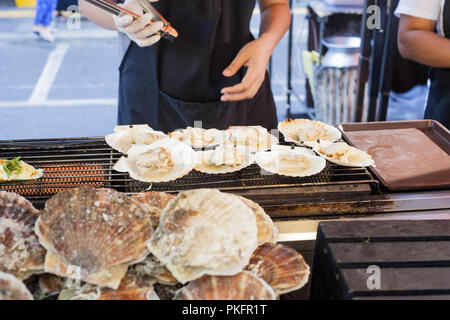 Cuisson des aliments de la mer thaïlandais. Gros pétoncles grillés sur la rue du marché à Phuket, Thaïlande Banque D'Images