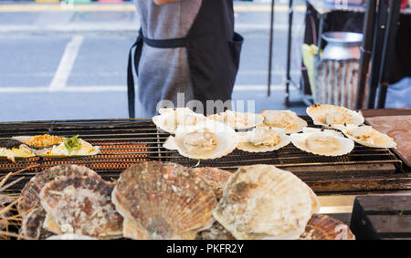 Cuisson des aliments de la mer thaïlandais. Gros pétoncles grillés sur la rue du marché à Phuket, Thaïlande Banque D'Images