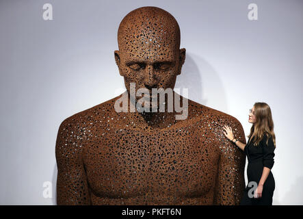 Un visiteur de l'Opera Gallery, Londres, place sa main sur l'épaule d'Young-Deok Seo travail 'Meditation 975" qui est faite de chaînes de vélos rouillés à l'Opera Gallery de Londres. Banque D'Images