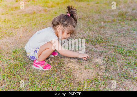 Portrait of cute little girl touching peu fourmis avec son doigt sur la colline sur la masse de sol ant Banque D'Images