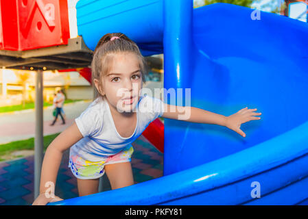 Portrait of cute little girl holding et de l'escalade pour atteindre les curseurs haut sur jeux pour enfants Banque D'Images