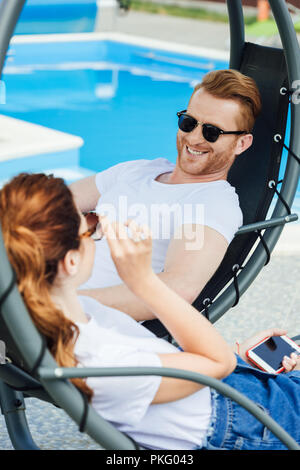 Jeune couple en blanc T-shirts flirter devant piscine Banque D'Images