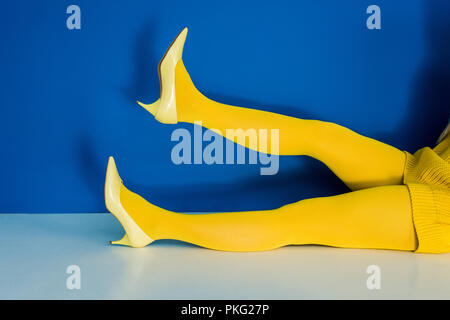 Portrait de femme jambes en collant et chaussures jaune sur fond bleu Banque D'Images