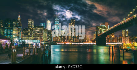 New York City Pont de Brooklyn et Manhattan skyline illuminée la nuit avec la pleine lune au-dessus. Banque D'Images