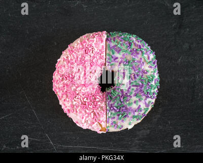 Deux demi-donuts couverte de glaçage et saupoudre de réunis pour créer tout un donut Banque D'Images
