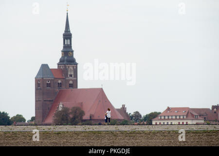 10 septembre 2018, la Saxe-Anhalt, Fischbeck poussettes : promenade le long de la digue terminée. Dans l'arrière-plan, la cathédrale de Klagenfurt (l) et la tour du château au-dessus du mur de la terre. Le nouveau 6,7 kilomètres de long l'article est d'être ouvert officiellement le 15 septembre 2018. L'ancienne digue a été rompu lors de l'inondation en 2013. D'énormes masses d'eau pénètre dans le Elb-Havel-Winkel. Enfin, les barges ont dû être détruites afin de combler la fracture aussi loin que possible. Photo : Klaus-Dietmar Gabbert/dpa-Zentralbild/ZB Banque D'Images