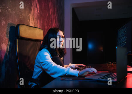 Jeune femme s'asseoir devant un ordinateur et ordinateur portable, php programmation programmation html Le cyberespace Concept. Looking at camera Banque D'Images