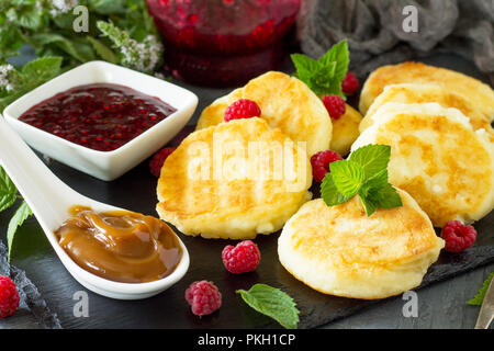 Arrière-plan de petit-déjeuner. Le fromage cottage maison des crêpes avec du lait condensé, la confiture de framboises sur ardoise, close-up. Banque D'Images