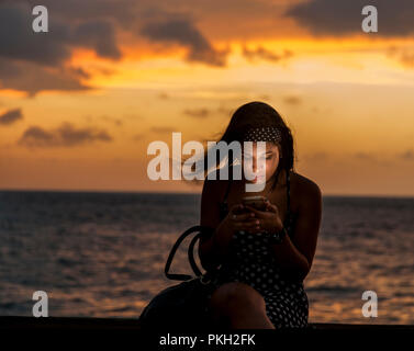 La Havane, Cuba. 22 juillet 2017 Maria Sotolongo surfe sur internet tout en restant assis sur le mur en Melacon La Havane Cuba. -Crédit David Creedon / Alamy Banque D'Images