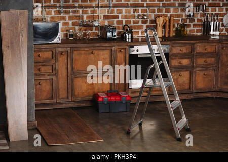 Intérieur de style loft avec cuisine escabeau, boîte à outils et des planches sur le plancher en stratifié Banque D'Images