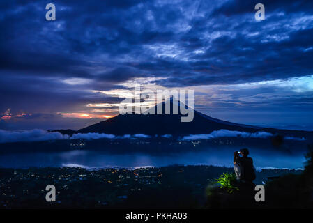 L'adherence homme photo de Agung volcan depuis le haut de Batur volcano au lever du soleil, Bali, Indonésie Banque D'Images