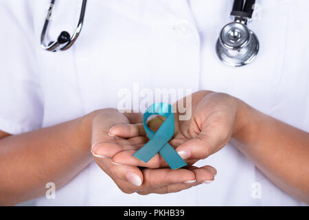 Close-up of a female Doctor's main avec ruban bleu sarcelle montrant de sensibilisation au cancer de l'ovaire Banque D'Images