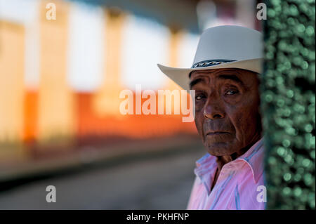 Un producteur de café colombien (caficultor) se cache dans l'ombre d'un brighly peints colonial house en Jericó, un village de la région du café (Zona cafétéria Banque D'Images