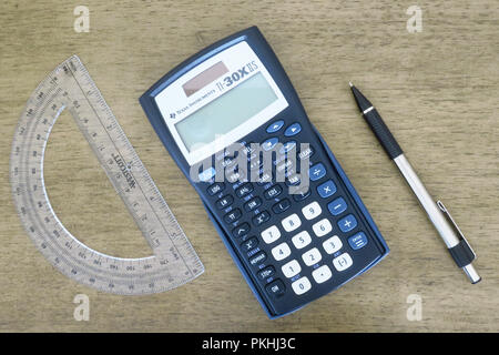 Une calculatrice, protactor, crayon, boussole, stylo et papier graphique disposés sur une table. Banque D'Images