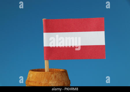 Un détail sur le papier l'Autriche drapeau sur bâton en bois dans le baril en bois. Fond bleu Banque D'Images