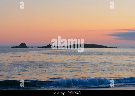 Le soleil se couche sur une mer de palourdes, les petites vagues qui, derrière une petite île de la baie Rock Banque D'Images