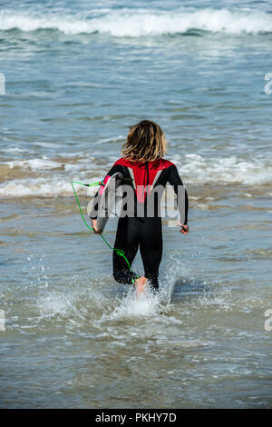 Jeune homme running in surf, plage de Fistral, Newquay, Cornwall Banque D'Images