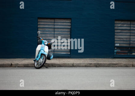 Scooter bleu garé en face d'un mur bleu Banque D'Images