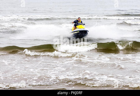 Jeune homme à cheval sur le jet ski effectuant des tours sur les vagues à l'été à la mer Baltique, la Lituanie. Banque D'Images