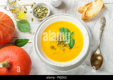 Potiron soupe végétarienne diététique crème purée à l'huile d'olive, des graines de basilic et d'une table en bois dans une assiette blanche. Selective focus Banque D'Images